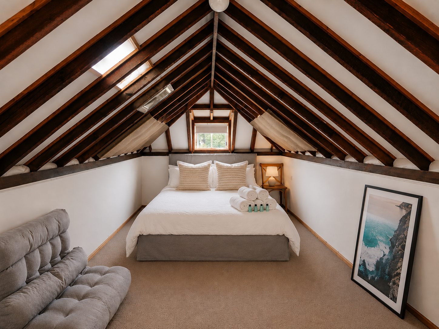 Loft bedroom with exposed timber beams and a skylight