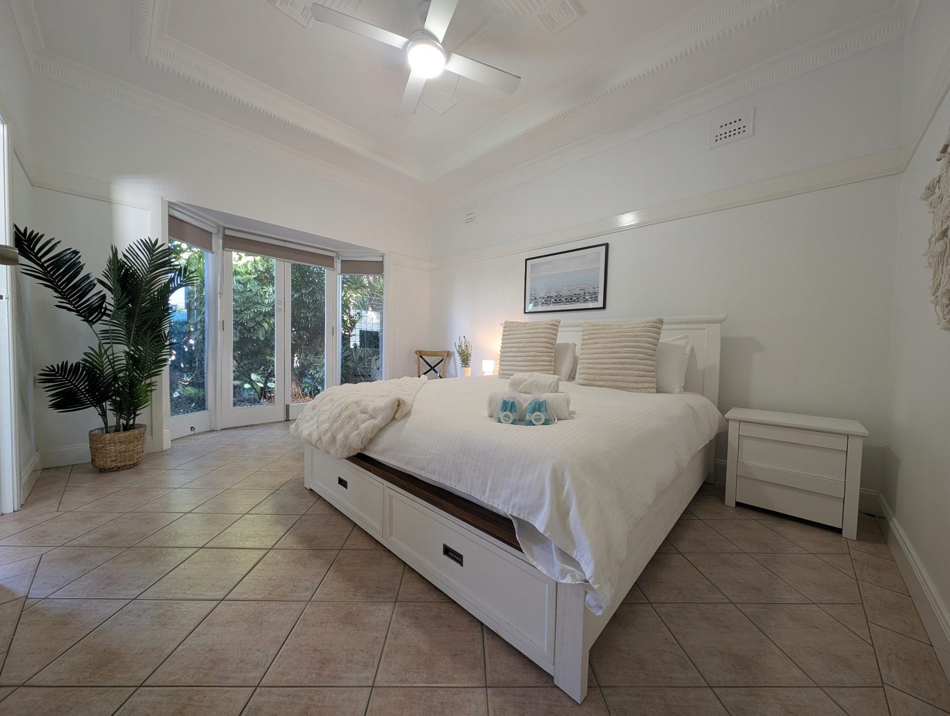 Main bedroom with white linens and French doors to the garden