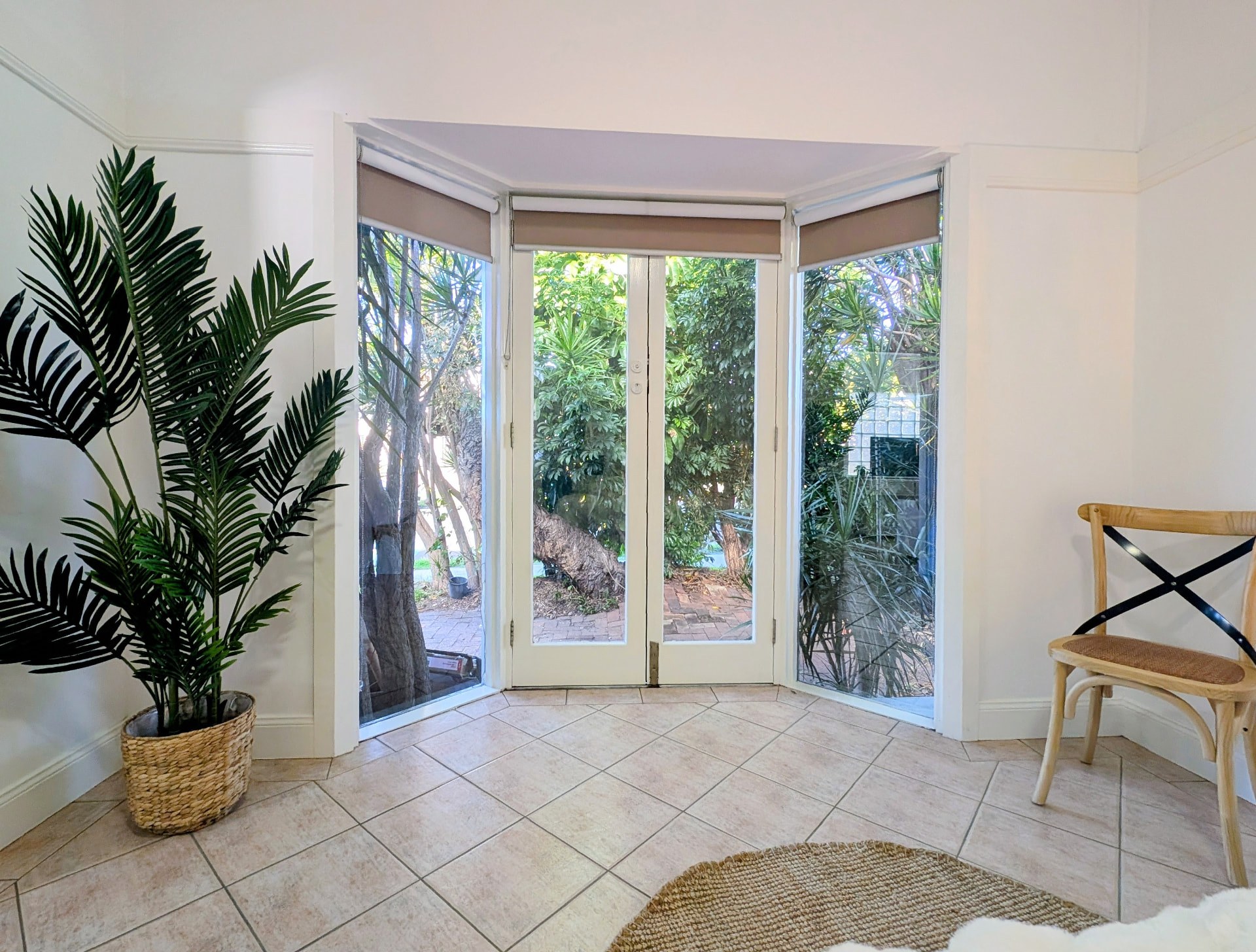 French doors opening onto the garden with a plant and timber chair
