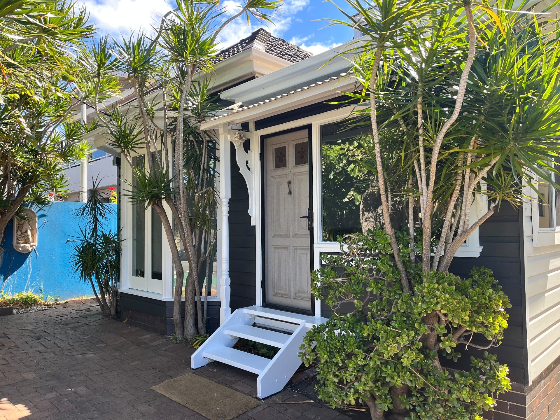 Cottage entrance with white steps and leafy garden